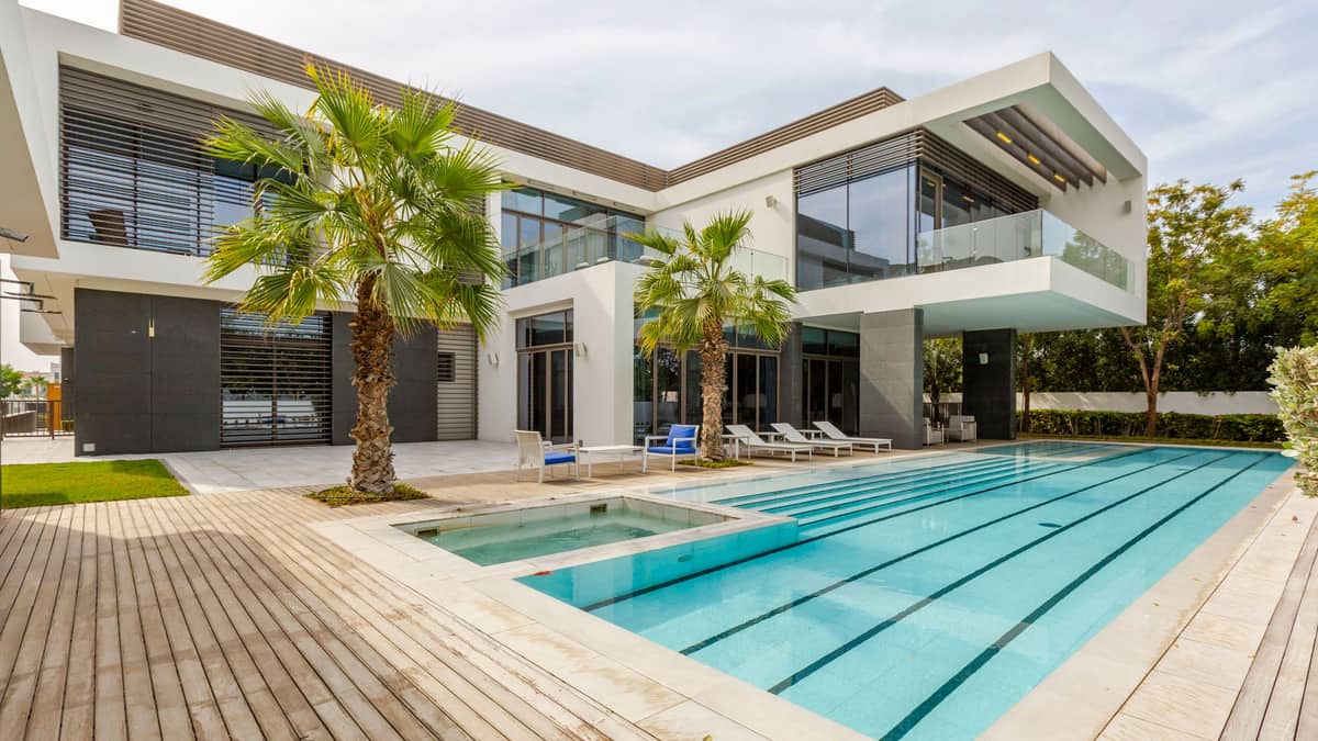 Villa garden in Emirates Hills with a tiled swimming pool, planted borders and a shaded pergola